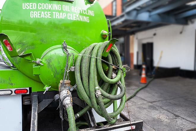 a technician pumping a grease trap in a commercial building in Scott